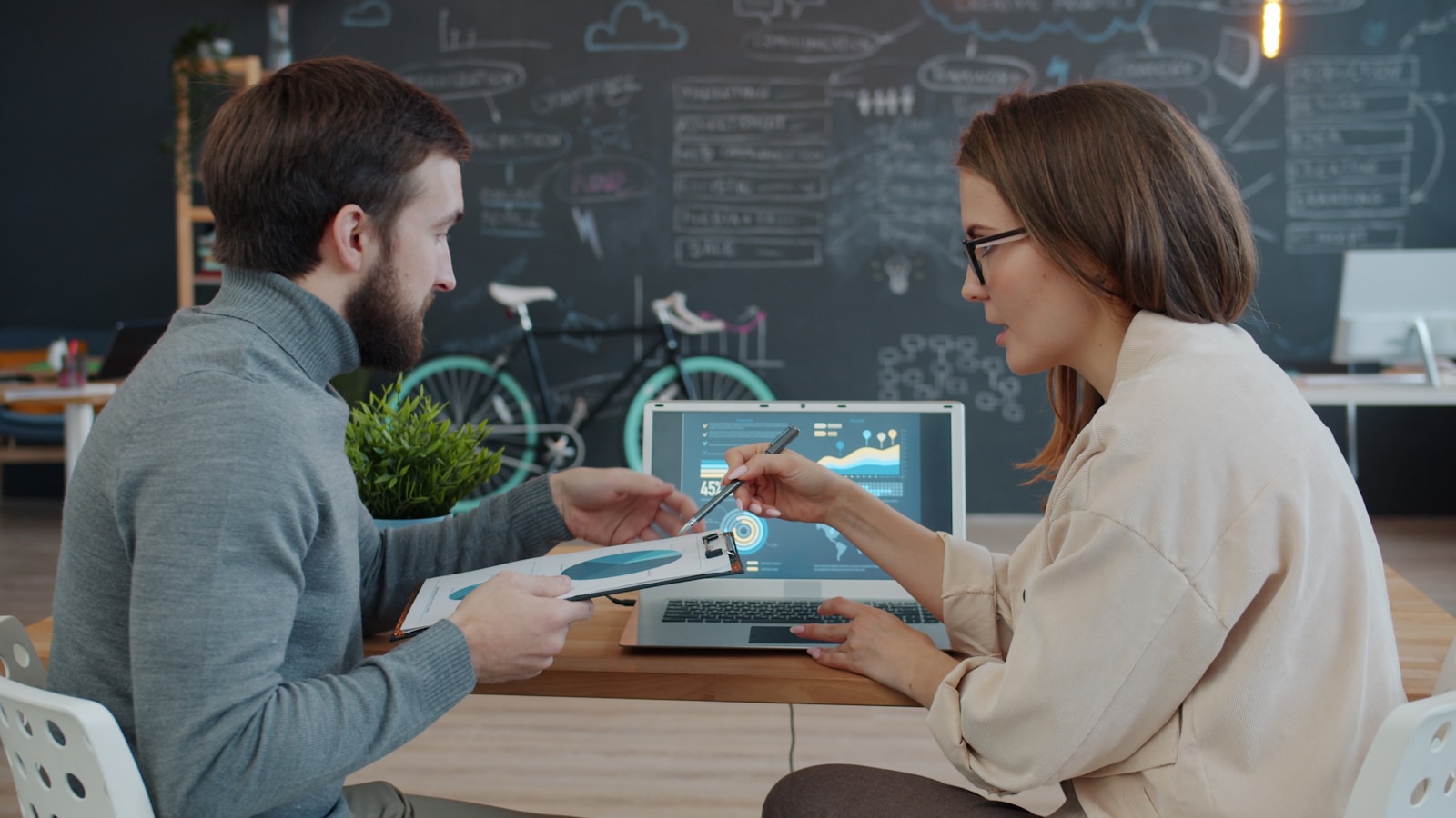 Two developers reviewing data together on a laptop at a shared desk, representing how teams evaluate AI gateway options