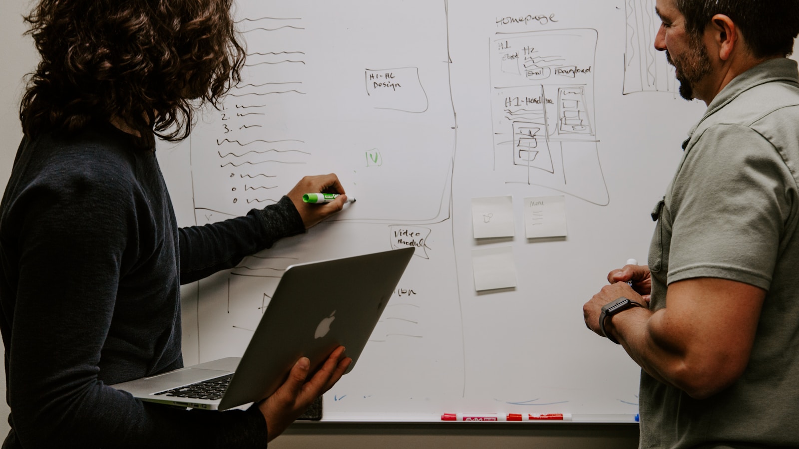 A developer standing beside a dry-erase board with a system diagram, planning the request path of an AI gateway architecture