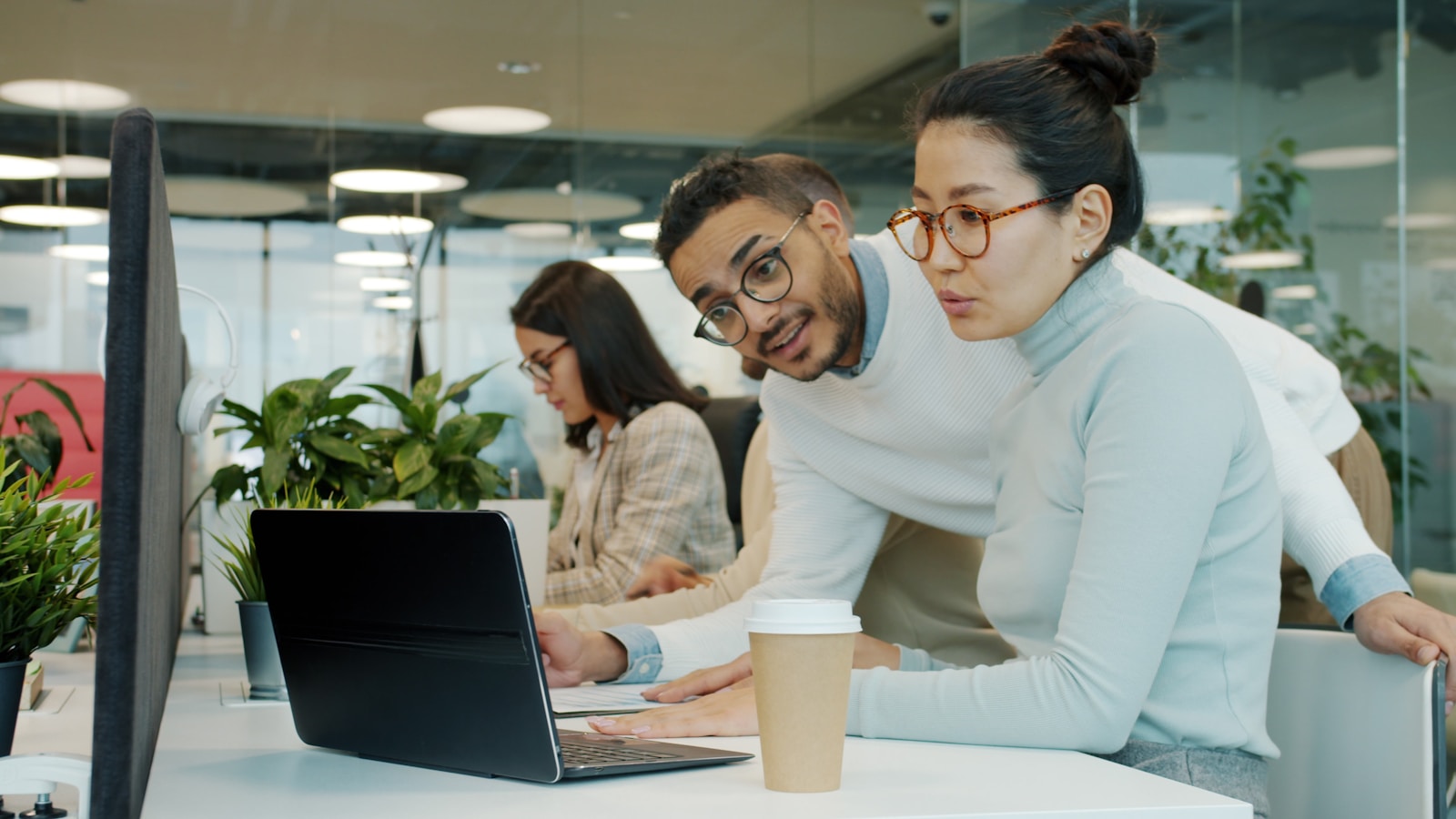 Two colleagues collaborating on a laptop in a modern office, reviewing whether to self-host an open-source AI gateway or use a managed one
